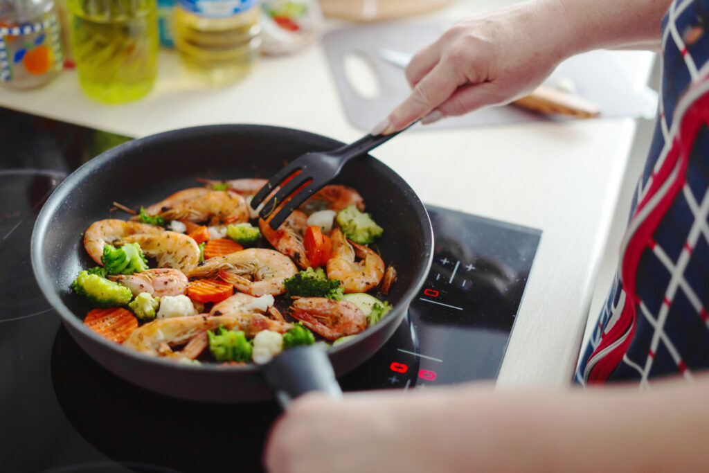 person cooking prawns in a fry pan