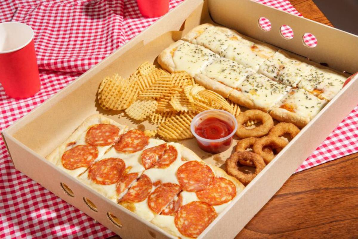 A food tray featuring pepperoni pizza, cheesy breadsticks, waffle fries, onion rings, and a side of marinara sauce, on a checkered tablecloth.