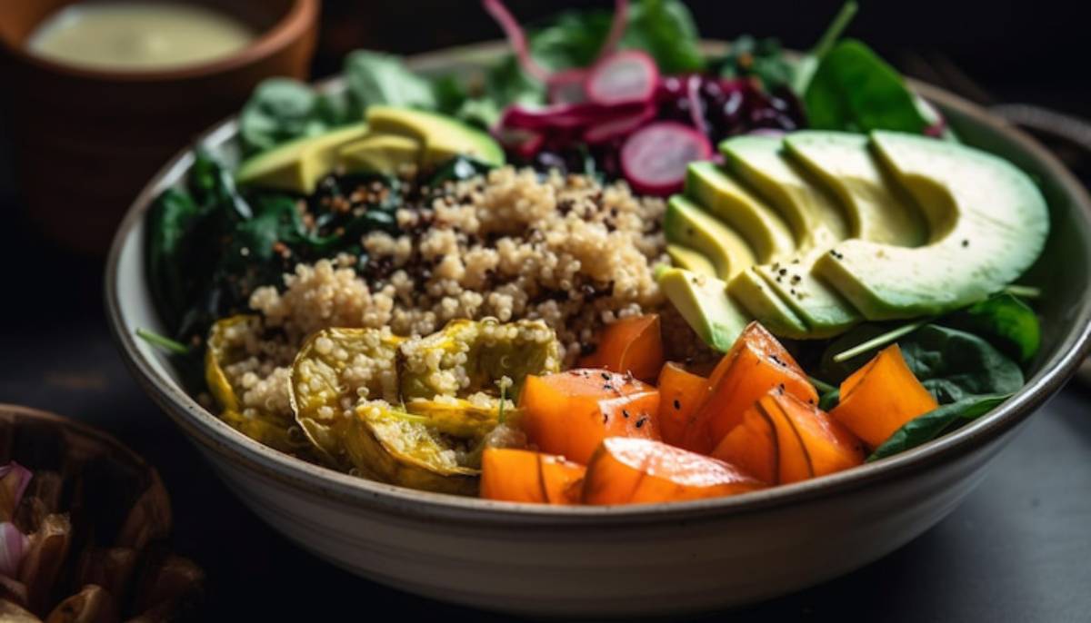 A vibrant bowl of quinoa topped with avocado, roasted squash, spinach, radishes, and orange slices, showcasing fresh, healthy ingredients.